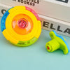 A bright yellow and pink glowing musical spinning top is shown next to its disassembled parts on a light blue surface.