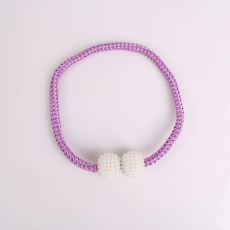 A purple braided tie-back clip featuring small white pearls.