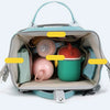 A light blue diaper backpack filled with various baby items including bottles and supplies.