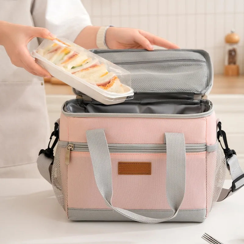 A pink insulated lunch bag is shown open, containing sliced food, being held by a person.