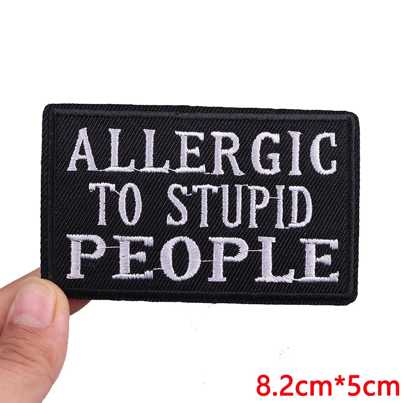 Black embroidered iron-on letter patch with white text that reads Allergic to Stupid People