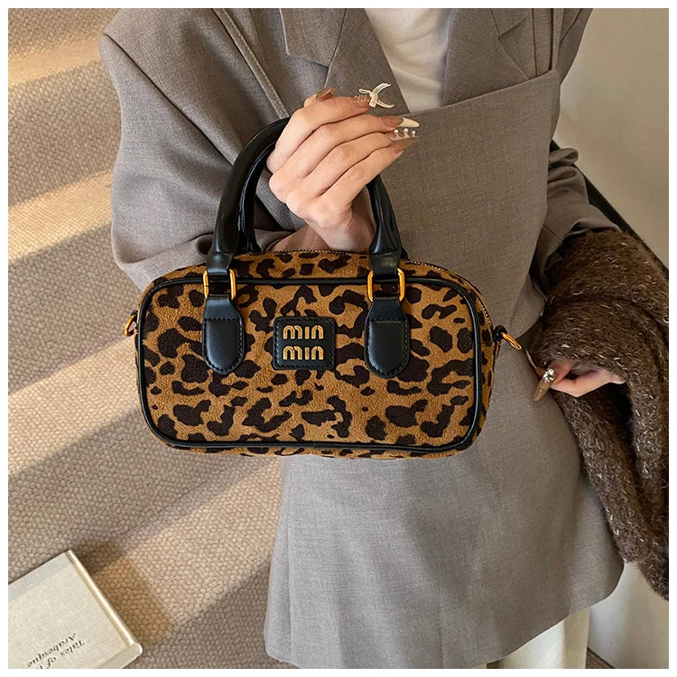 A close-up of a brown leather retro leopard print hobo satchel bag carried by a person in a gray blazer.