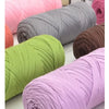 A collection of thick, colorful yarn skeins in shades of pink, green, gray, and purple for knitting and crochet projects.