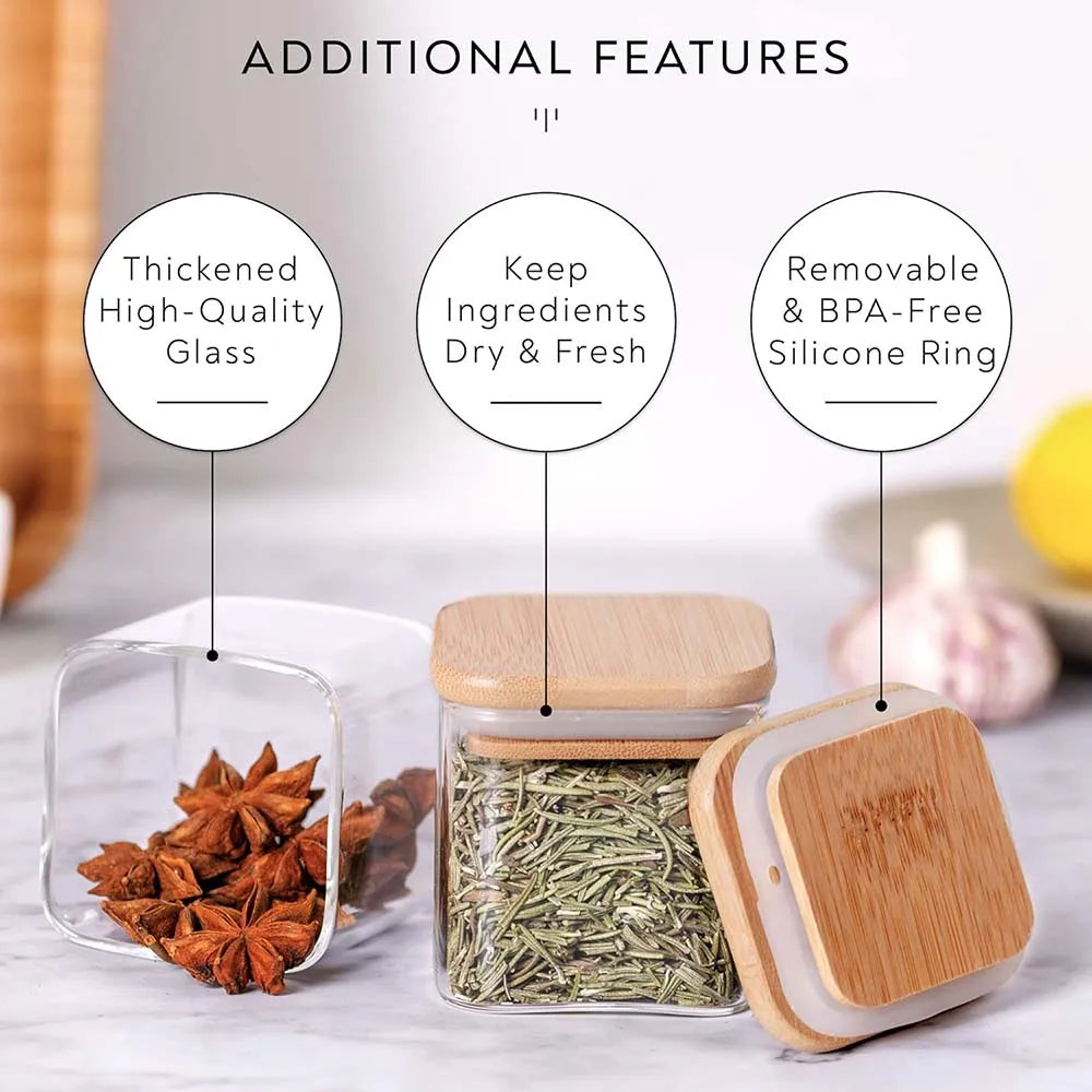 Square glass spice jars with bamboo lids and labels shown next to dried spices on a white surface
