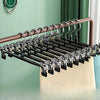 A set of five anti-slip stainless steel hangers with clips for pants and skirts displayed on a wooden rod.