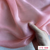 Close-up of pink mulberry silk chiffon fabric being held and draped.