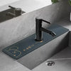 A matte black faucet mounted on a dark blue mat in a modern bathroom setting.