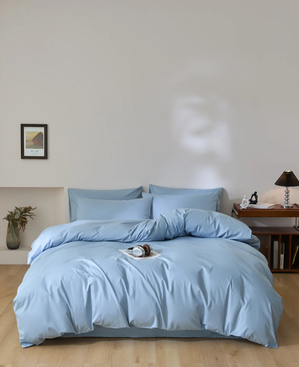 A light blue quilted duvet cover set with matching pillowcases on a bed against a white wall.