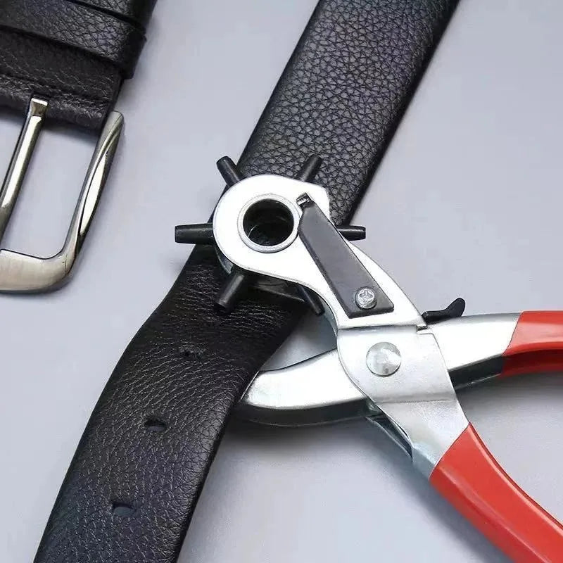 A close-up of a black leather strap with a silver and red multifunctional hole punch pliers attached.