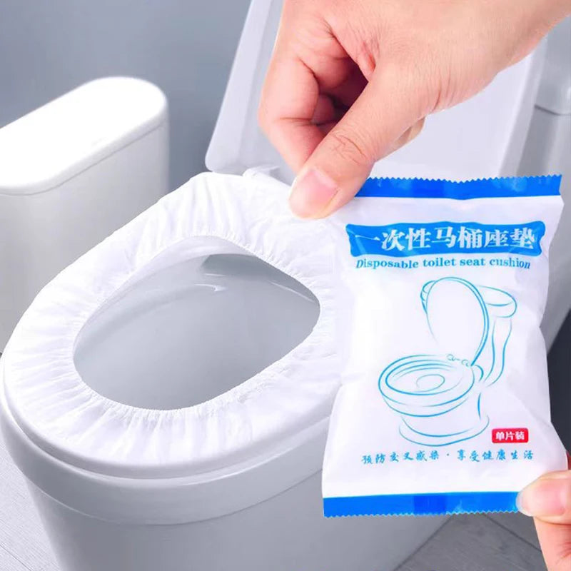 A hand is placing a package of waterproof disposable toilet seat cushion onto a white toilet bowl.