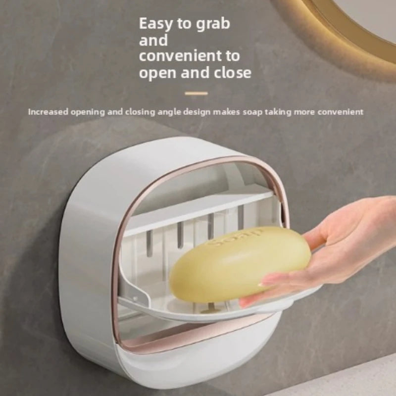 A hand is opening a wall-mounted soap holder with a lid and drainage feature.