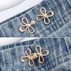 Gold clover-shaped adjustable buckle attached to denim fabric