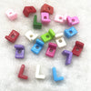 A collection of 10 mixed alphabet letter beads in various colors and shapes scattered on a white, fluffy surface.