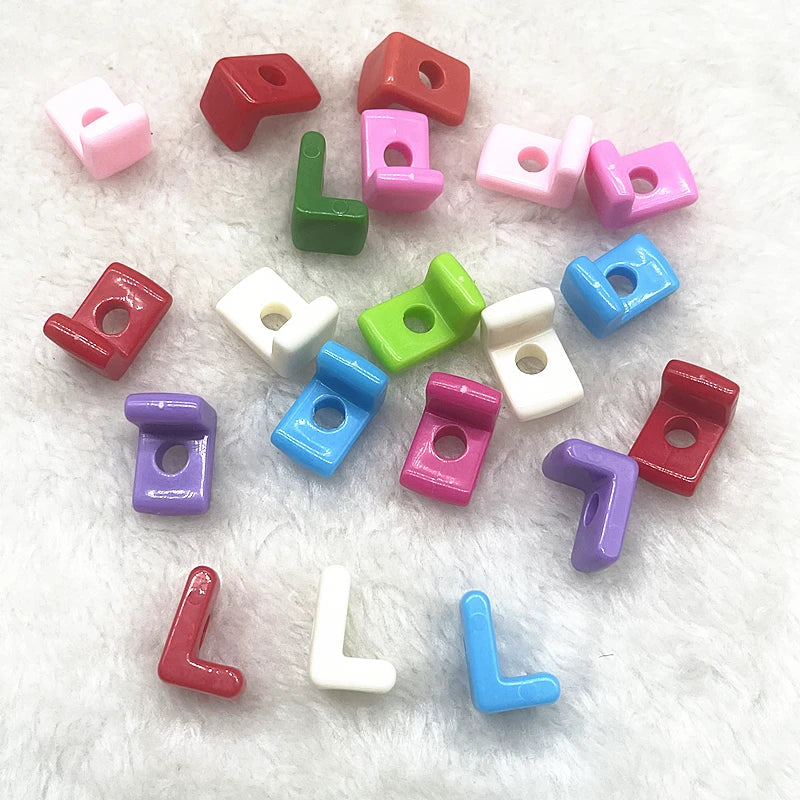 A collection of 10 mixed alphabet letter beads in various colors and shapes scattered on a white, fluffy surface.