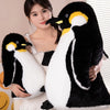 A woman is holding a black and white penguin plush toy.