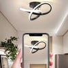 A hand holds a smartphone displaying a modern clover LED ceiling light fixture installed in a room.