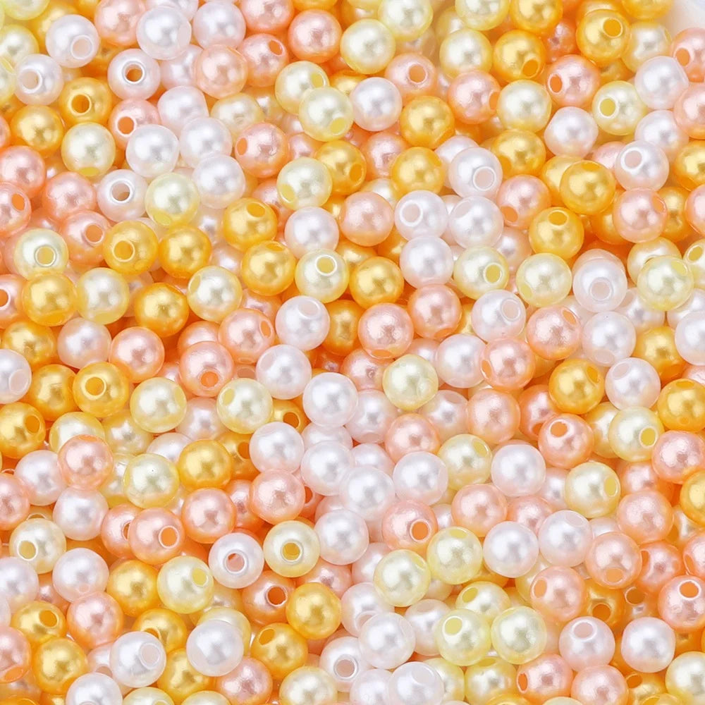 A close-up of round imitation pearl beads in shades of pink, peach, and yellow.