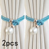A set of two turquoise rope and pearl curtain tie-backs used to secure light beige curtains.
