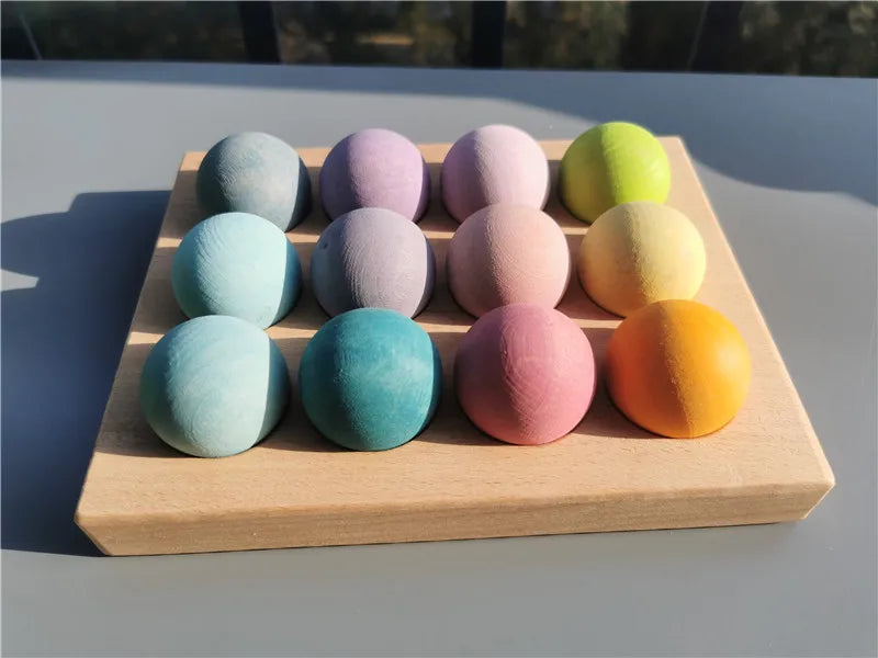 Eine Holzschale hält zehn farbenfrohe, kugelförmige Blütenblätter in verschiedenen Pastell- und Gelbtönen.