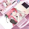 A drawing of an anime girl with pink hair relaxing on a pink desk mat next to various stationery items and a tablet.