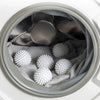 A close-up view inside a white container showing reusable white laundry balls nestled in a gray cloth.