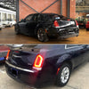 A black Chrysler 300 sedan with aftermarket rear bumper reflector light covers displayed indoors.