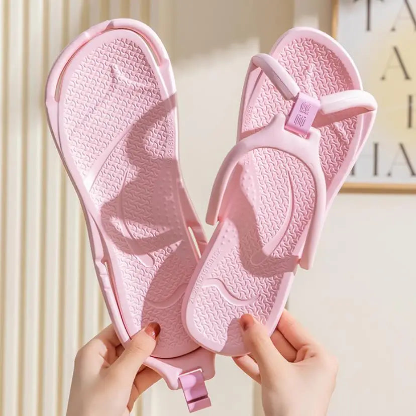 A pair of pink foldable EVA travel slippers being held by hands.