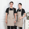 A man and a woman model an adjustable beige cotton apron for kitchen or work use.
