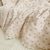 A soft, light beige floral muslin baby blanket folded and draped on a white surface.