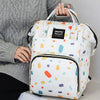 A white and colorful patterned waterproof backpack diaper bag with black trim being held by a person.