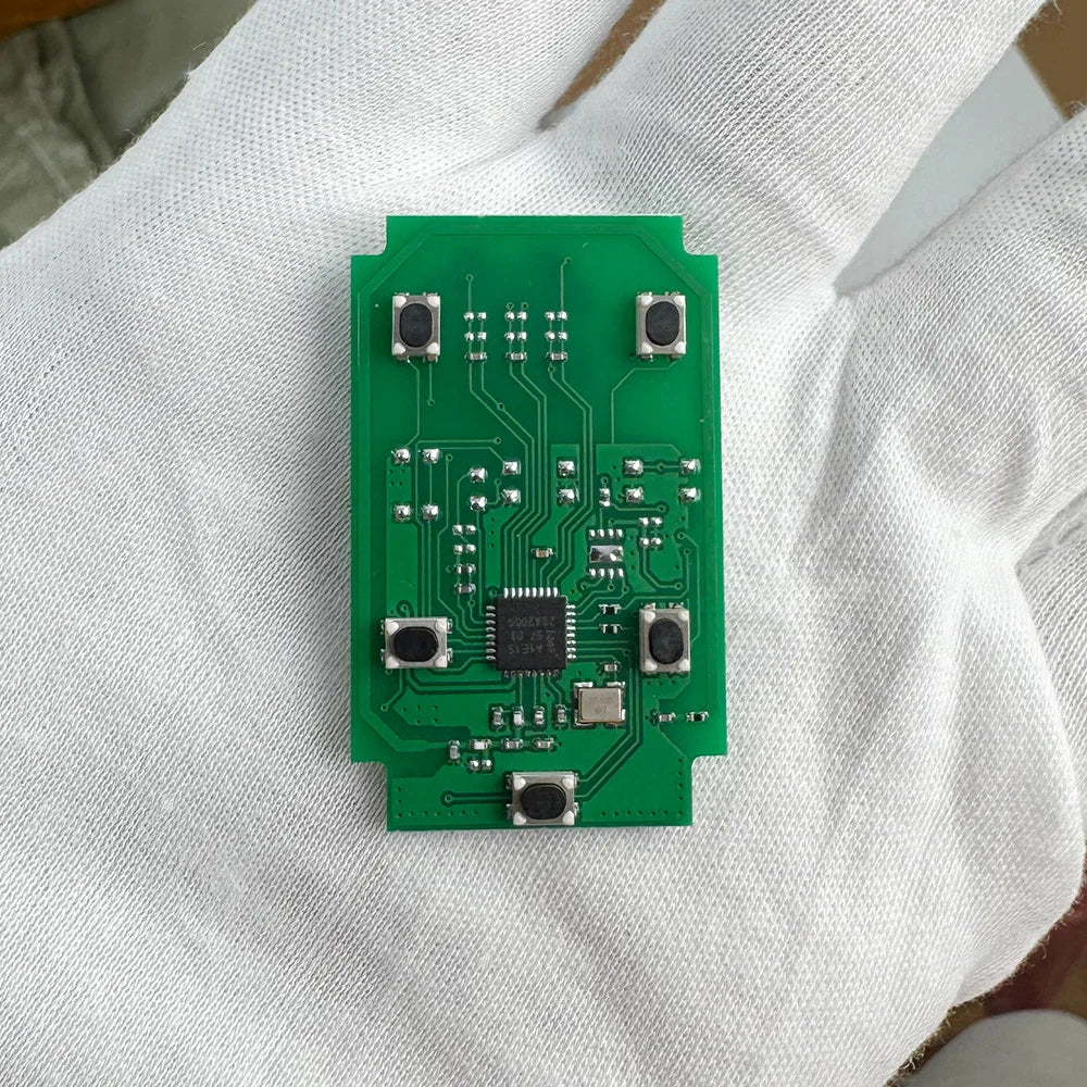 A green electronic circuit board is held in a person's hand.