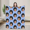 A colorful throw blanket featuring a repeating pattern of cartoon characters with black hair and glasses on a blue background