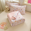 A pink and white patterned duvet with lace trim is displayed on a bed, alongside a small stuffed animal.
