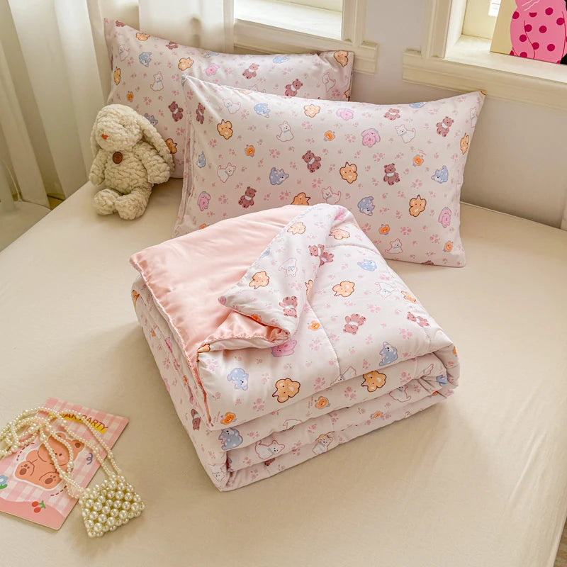 A pink and white patterned duvet with lace trim is displayed on a bed, alongside a small stuffed animal.