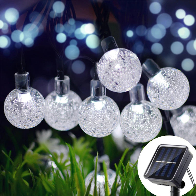 String lights featuring crystal ball-shaped solar-powered fairy lights illuminating greenery at night
