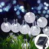 String lights featuring crystal ball-shaped solar-powered fairy lights illuminating greenery at night