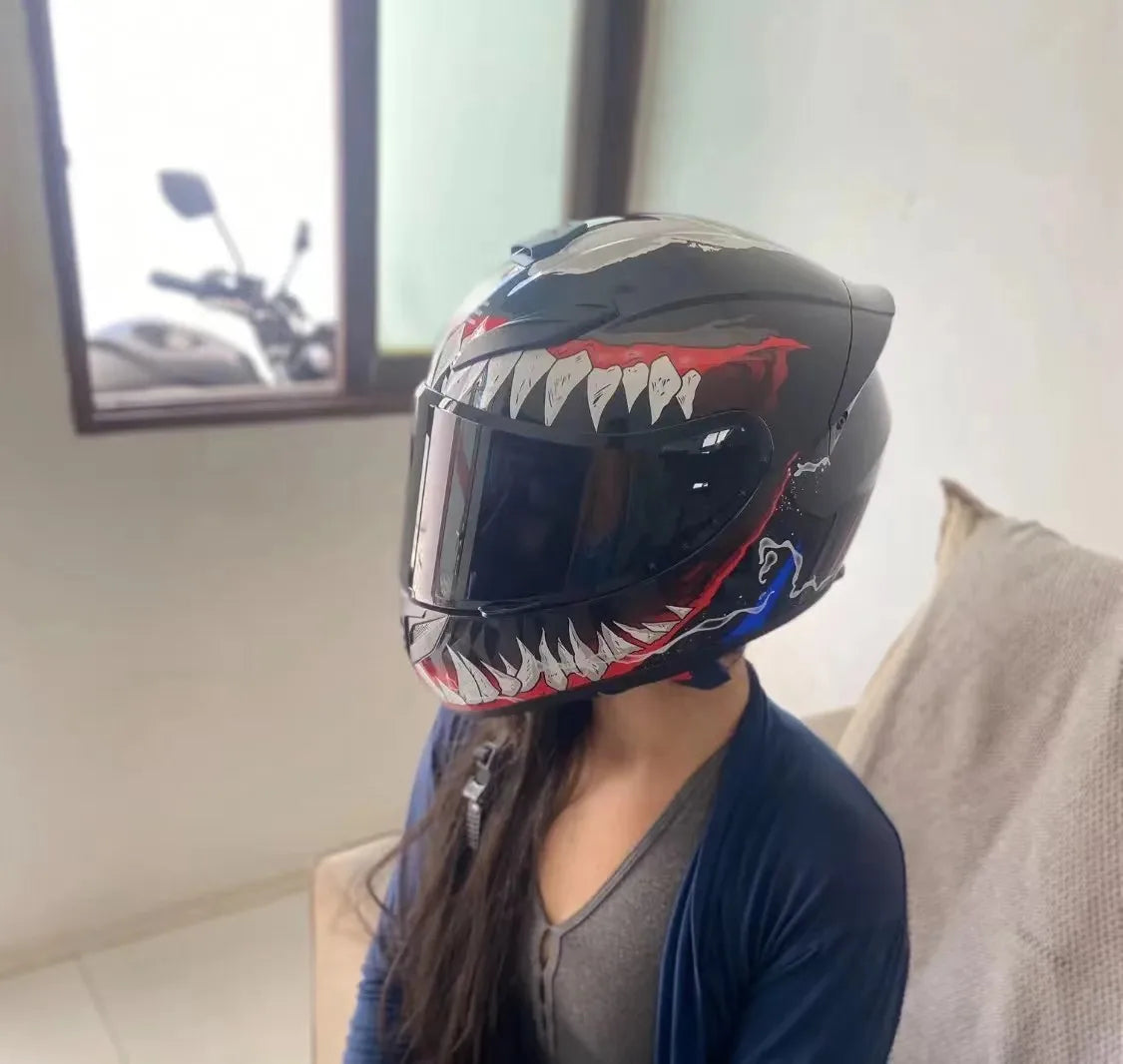 A close-up of a black full-face motorcycle helmet with a fierce, toothy design and red accents.