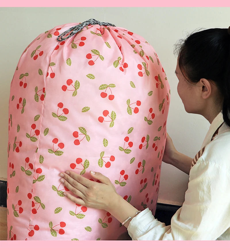 A pink drawstring laundry bag with a cherry pattern is being held by a woman.