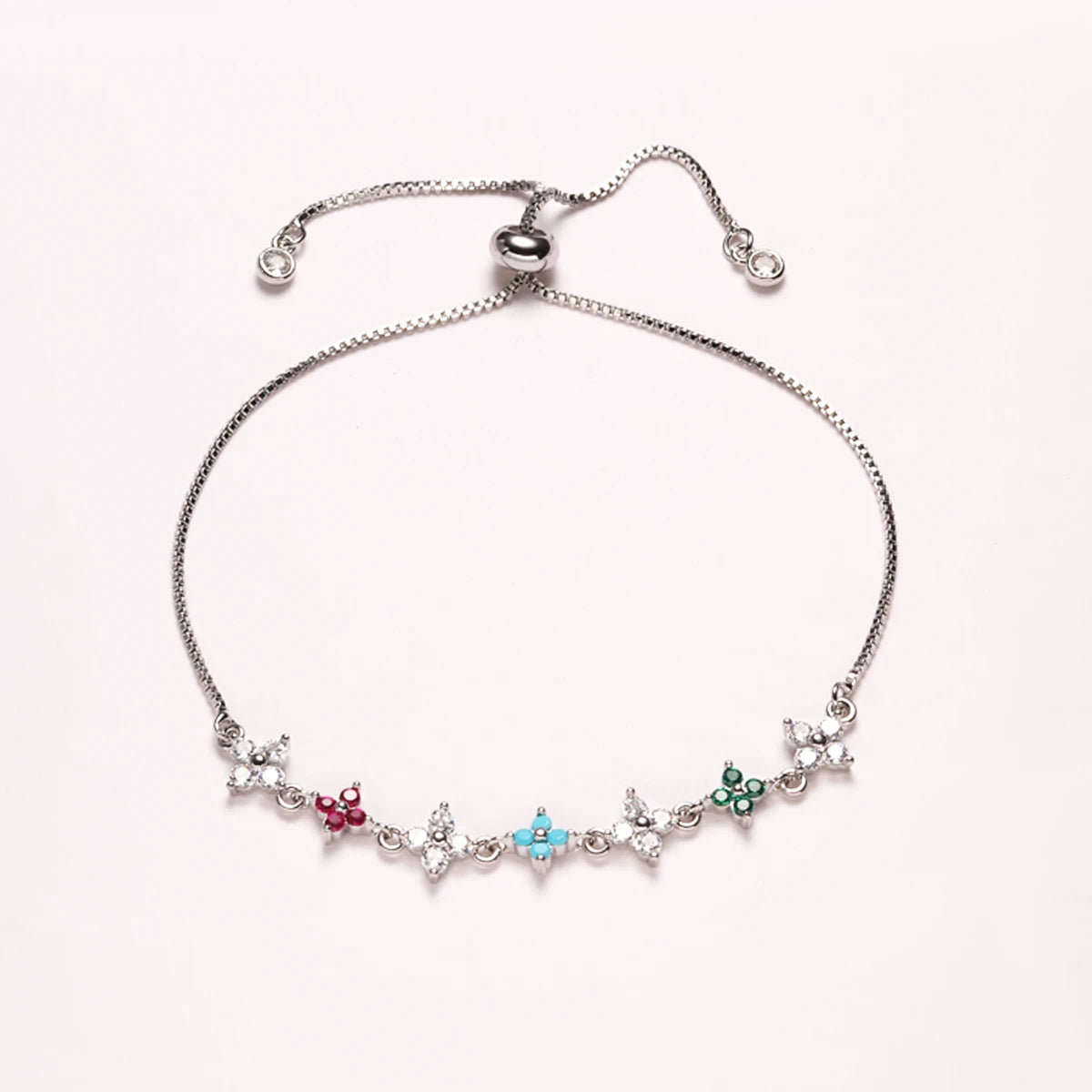 A delicate silver bracelet featuring a chain and small clover-shaped cubic zirconia charms.