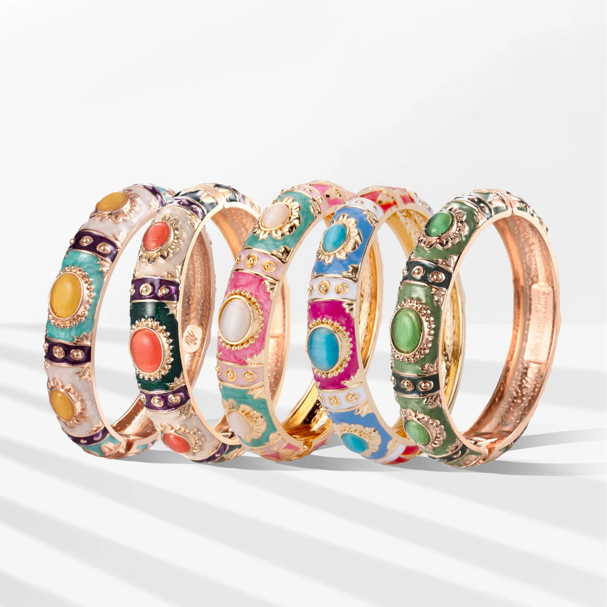 A collection of rose gold plated bangles featuring colorful enamel designs and gemstones.
