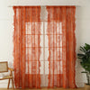 Orange sheer curtains with floral embroidery and ruffled lace detailing hanging in a window.