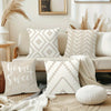 A set of decorative pillows in cream and white geometric patterns displayed on a light-colored sofa.