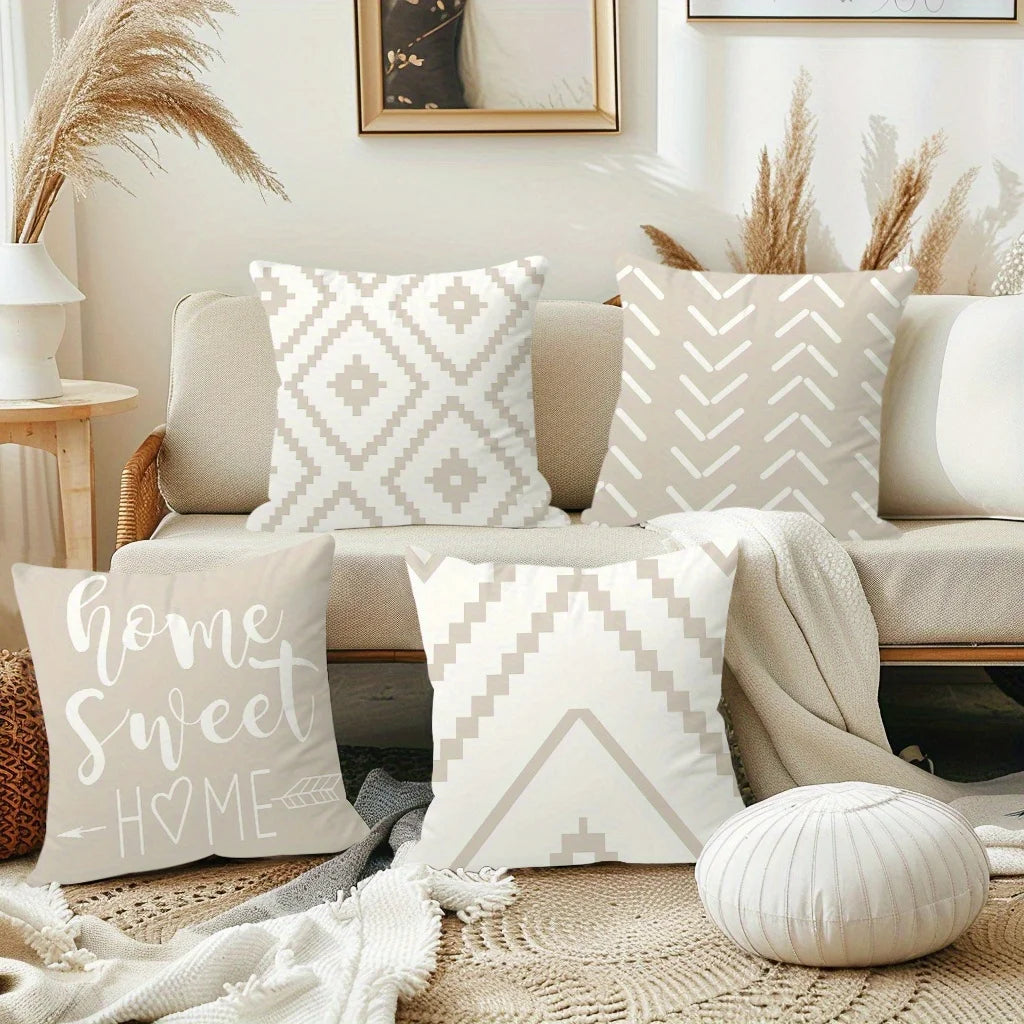 A set of decorative pillows in cream and white geometric patterns displayed on a light-colored sofa.
