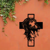 Silhouette de la tête et de la barbe de Jésus en métal noir avec une croix sculptée dans un mur de terre cuite recouvert de l