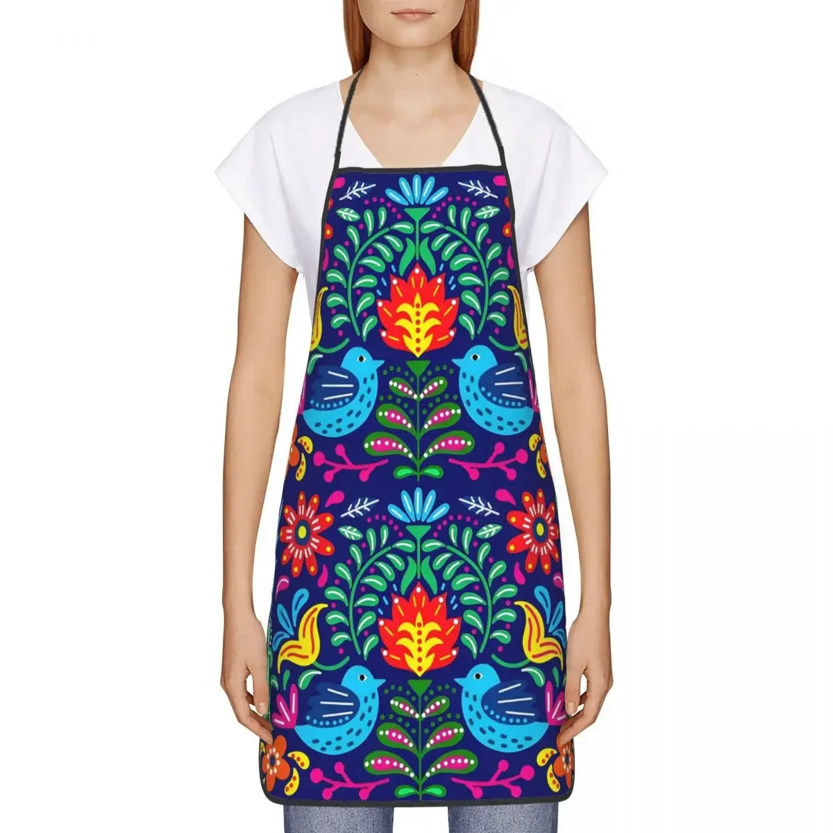 A woman wearing a vibrant purple and green Mexican floral art apron over a white shirt.