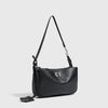 A black leather tote bag with a long strap and a metal buckle displayed against a light gray background.