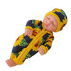 A baby doll wearing a yellow and blue sunflower jumpsuit outfit and matching hat.