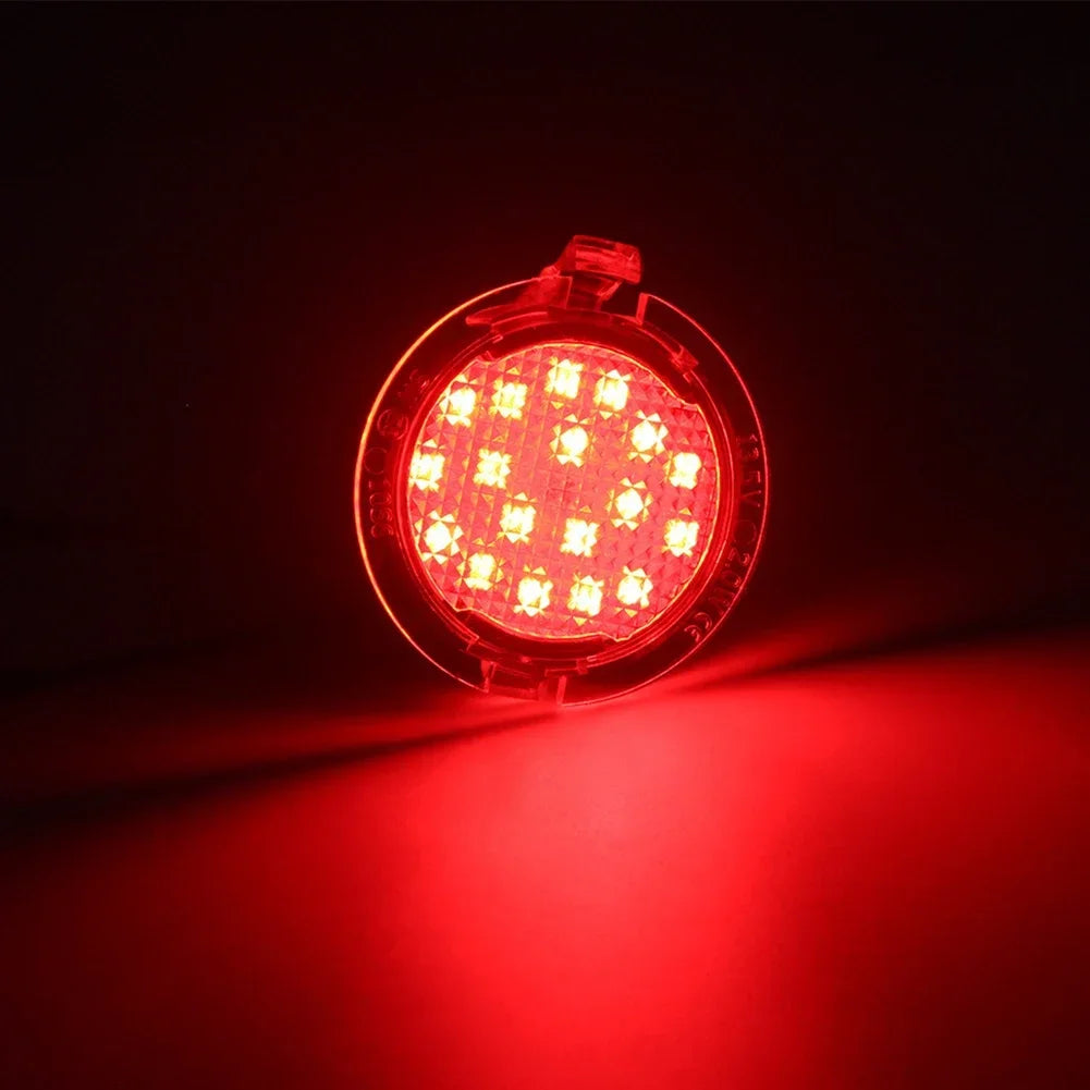 A bright red LED puddle light mounted on a circular housing, illuminating a surface.