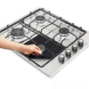 A hand is adjusting a reusable gas stove burner protector on a stainless steel cooktop.