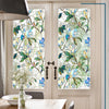 A close-up view of a floral stained glass window film applied to a white door, featuring blue and green leaves and flowers.
